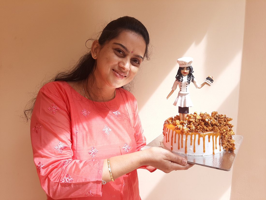 The baker behind ArtsyTartsy holding a caramel drip cake